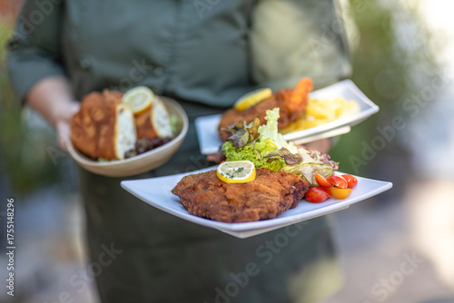 Foto Waiter serving vegetarian and classic cordon bleu with potato salad and lemon ga