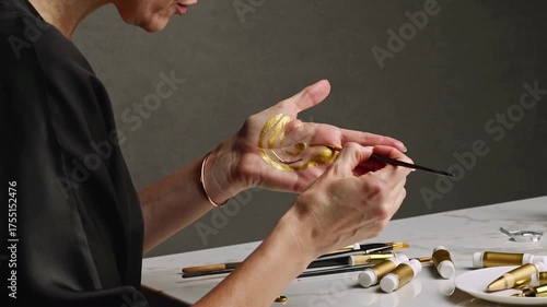 Applying gold paint on hand with brush