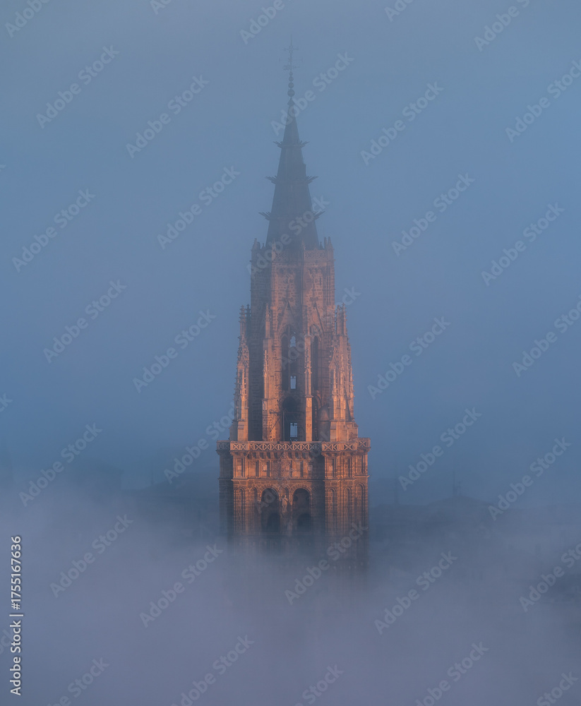 Naklejka premium Toledo Cathedral tower glowing in sunrise fog, Castilla-La Mancha