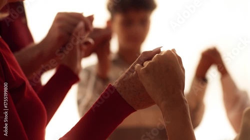 Family members gather around a table, holding hands in unity, expressing gratitude and warmth. The atmosphere is joyful as they prepare for their Thanksgiving celebration.