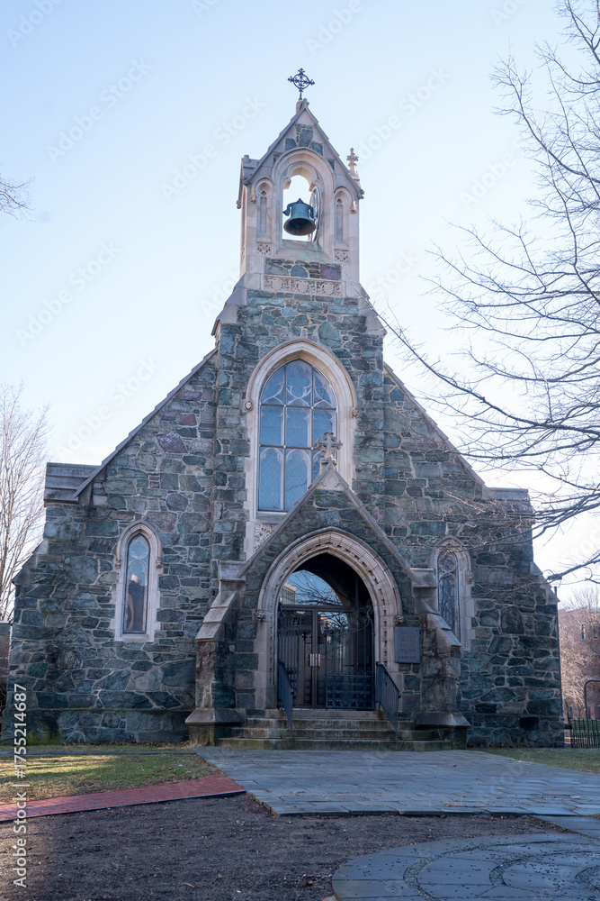 Fototapeta premium Front view of Swedenborg Chapel in Cambridge, Massachusetts, showcasing its stone Gothic Revival architecture, pointed arch entrance, and bell tower under a clear blue winter sky