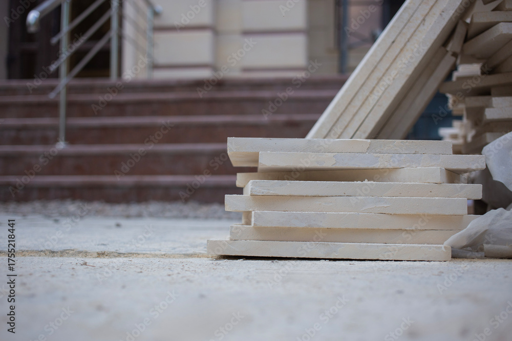 Obraz premium Large slabs of natural marble stacked at a renovation site against the backdrop of a porch under construction, close-up, the background is blurred with a bokeh effect