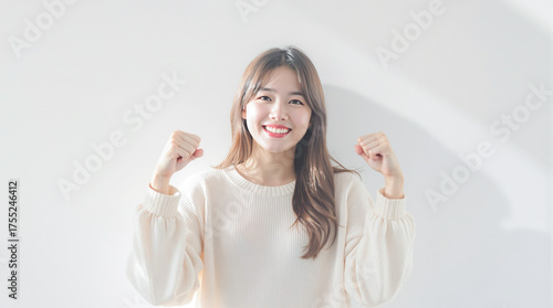 白背景に笑顔でガッツポーズをする若いアジア人女性