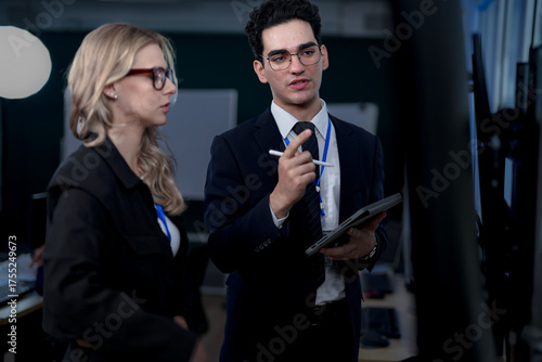 Vászonkép A senior software developer leads a code review session, pointing to a specific function on the screen to explain its logic and syntax to a junior engineer before a major deployment