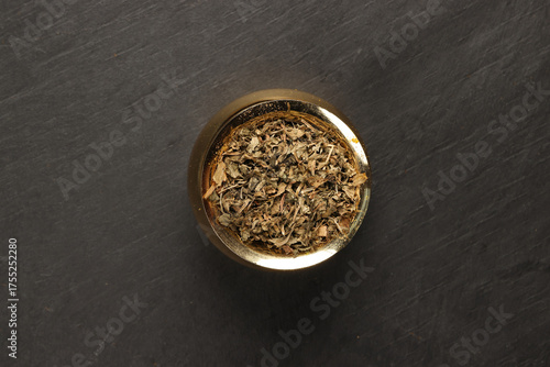 Wallpaper Mural dry green fenugreek leaves powder in a brass metal pot on a dark surface with a clean and neat appearance striking contrast vibrant spice Torontodigital.ca