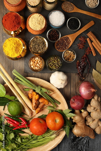 Overhead flat lay vibrant colourful spices herbs fresh produce vegetables legumes on wooden table spread splash smoking spice mix dark black slate metal clay pot palm leaf plate board copy text frame