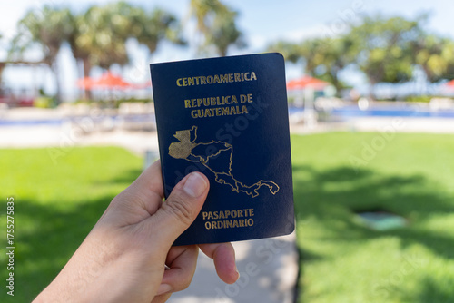 Photograph of a Guatemalan Central American passport held in one hand with a blurred beach background.