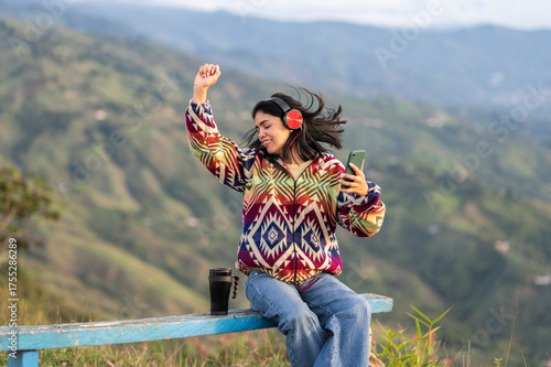 Latin woman dancing and listening to music with headphones in the mountains