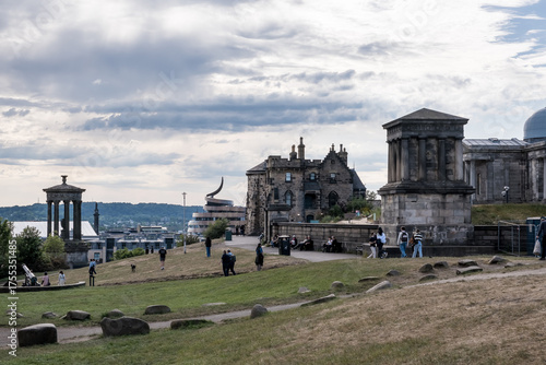 Edinburgh, Scotland – View of Calton Hill's iconic monuments the historic spires and rooftops of Edinburgh's Old Town visible in the far background.