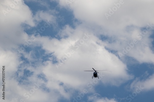 A chopper in flight in a cloudy and blue sky silhouetted image in horizontal format