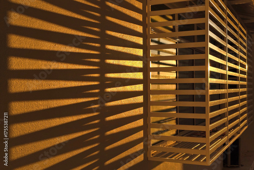 Golden Sunlight Casting Shadow Lines Through Window Grille on Wall