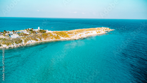 Isla Mujeres, Cancun, Mexico - Beautiful blue ocean with a small island in the middle. The island is surrounded by water and has a lighthouse on it. The sky is clear and the water is calm