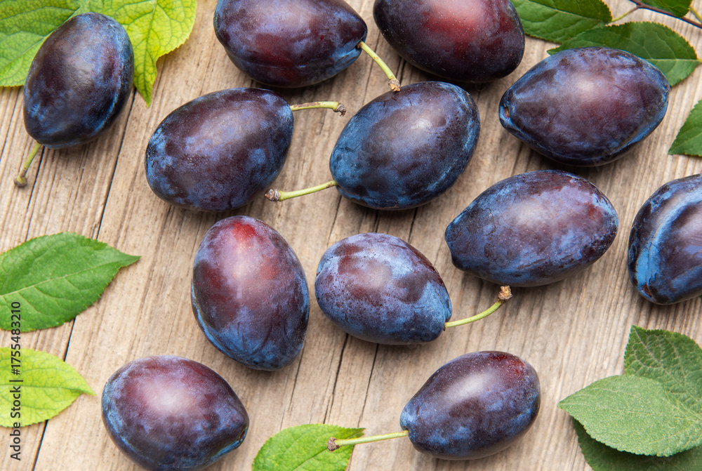 Fototapeta premium Ripe purple plums fallen on wooden table