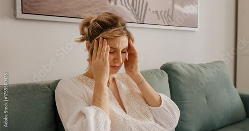 Obraz na plátně Pregnant woman sitting on sofa suffering for headache or catching a cold