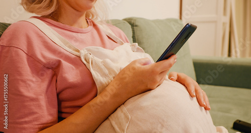 No face pregnant woman using phone and stroking her tummy. Close up of bored pregnant woman uselessly scrolling phone.