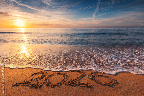 Ocean Beach Sunrise with 2026 Happy New Year Text Written in Sea Sand and Splashing Ocean Waves on the Shore concept for beautiful new beginning