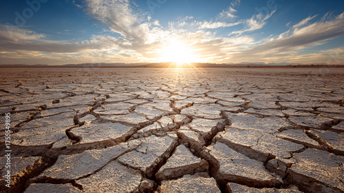Cracked earth desert landscape at sunset, symbolizing drought, climate change, and environmental devastation.