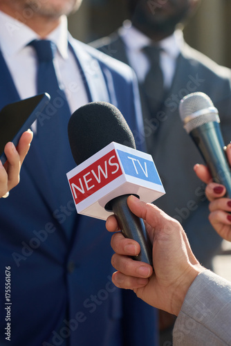 Bild auf Leinwand Caucasian middle aged man wearing suit speaking to journalists holding microphon