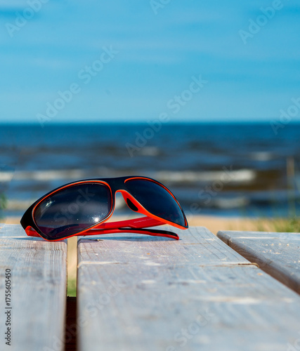 Sunglasses on wooden resting table on sandy beach of Jurmala - famous Baltic tourist  resort in Latvia, Europe. Sand beaches cover more than 26 km of coastline