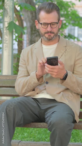 Young Man Using Smartphone while Sitting Outdoor, Vertical Video
