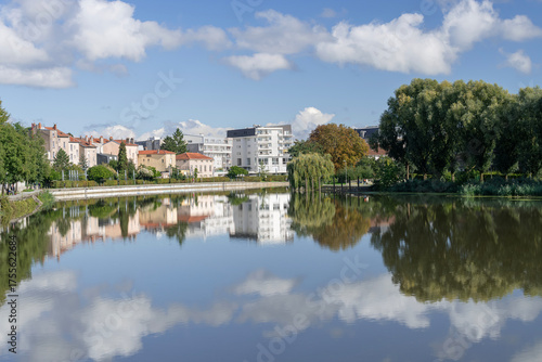 Saint-Max, France - September 27th 2025 : View of the banks of the La Meurthe river at Saint-Max with modern buildings, trees and reflections on the water.