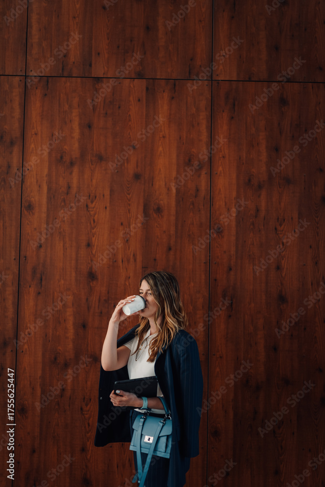 Fototapeta premium Businesswoman drinking coffee and holding tablet in modern office