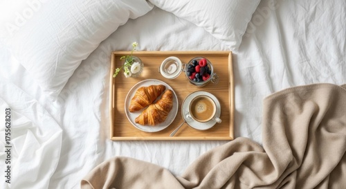 Breakfast in bed with croissants, berries, coffee and flowers on a wooden tray