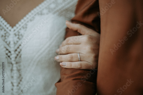 Fotografia Détails d'une mariée en robe de dentelle posant sa main sur le bras de son époux