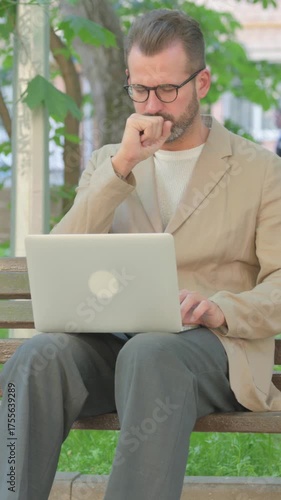 Young Man Coughing while Using Laptop Sitting Outdoor, Vertical Video