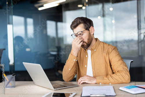 Tableau sur toile Businessman feeling overwhelmed and tired, rubbing his eyes from eye strain and