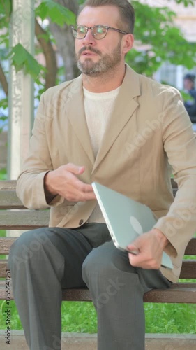 Young Man Leaving Outdoor Bench after Using Laptop, Vertical Video