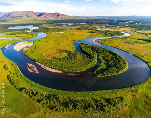 Winding river through lush green valley with distant mountains