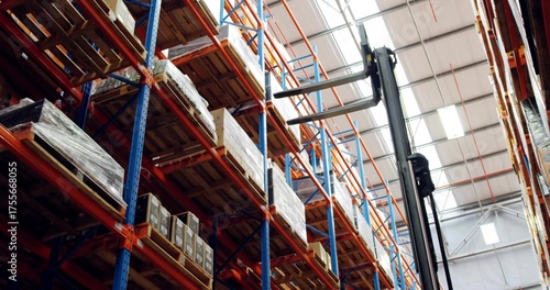 Showcasing pallet racks holding pallets and cardboard boxes in warehouse, with forklift mast