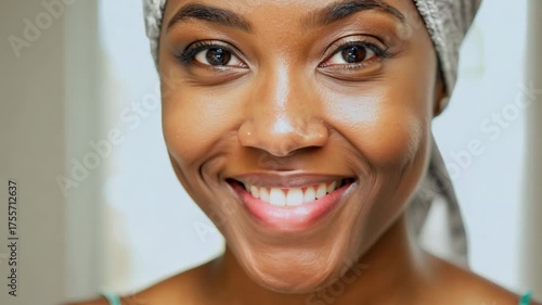 30 year old African American woman in bathroom with a towel on her head. Skin care concept. Woman with towel on head refreshes her skin in a bright, peaceful setting.