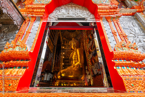 A golden Buddha seen through the temple window, glowing with peace and sacred beauty at Wat Si Don Mun, Chiang Mai.