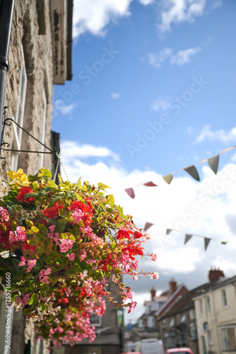 Obraz na plátně Hanging flower basket in Welsh village street with bunting