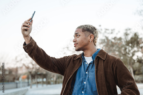 Young Latin American Man Taking a Selfee with His Cell Phone in a Park