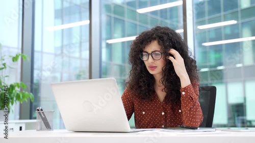 Frustrated businesswoman having difficulty making transaction using laptop sitting at desk at workplace in a modern business office. Confused female worker having problems working online on computer