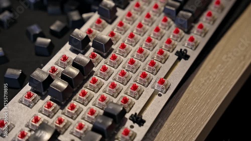 Close up view of man repairing mechanical keyboard, installing keycaps on red switches. Selective focus on hands and keys, concept of electronics, DIY, and computer maintenance