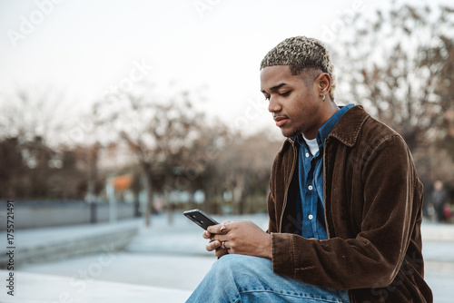 Young man in a park concentrated looking at his mobile
