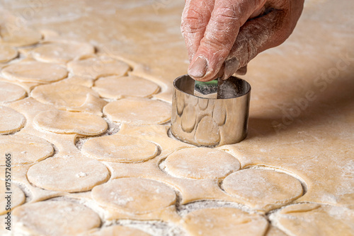 Canvas Print Preparation of the dough for baking, large piece of the dough is on the table and the chef cuts out small circles on it with an iron shape