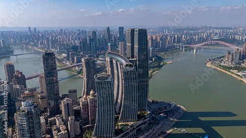 Aerial view of a striking modern architectural landmark in Chongqing, China. A skybridge connects multiple towers over the river confluence on a sunny day, showcasing innovative design