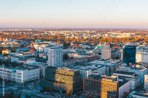 Aerial view of Warsaw, Poland city center at sunset, with mix of historical and modern buildings in warm light. Vistula River valley and part of the city densely built urban landscape