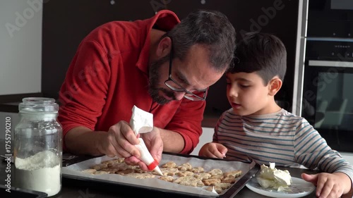 Dad and son decorating holiday cookies with frosting