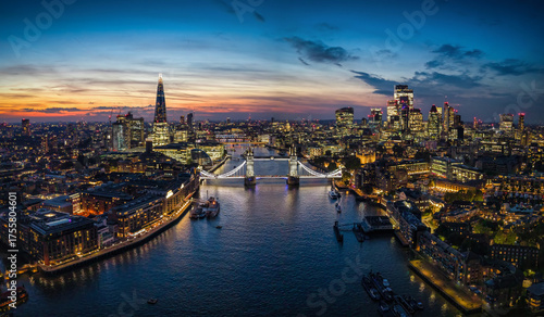 Wide, panoramic evening view of the illuminated skyline of London, United Kingdom, with Thames river, Tower Bridge and City skyscrapers