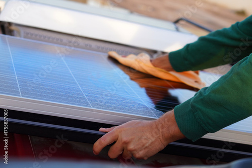 renewable energy. sustainable living. a man's hands cleaning the solar panel on his camper van