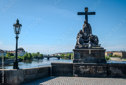 Statue of the Lamentation of Christ (Pietà) on Charles Bridge over the Vltava River in Prague Old Town, Czech Republic, photographed on a bright morning.