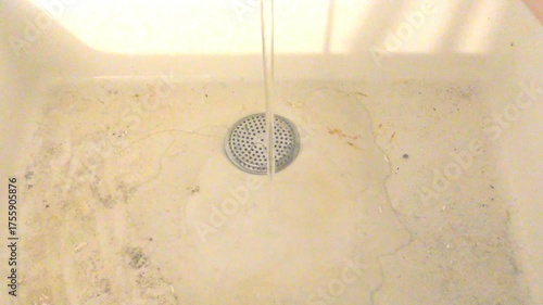 Dirty water from the tap. Rusty water flows into a dirty bathtub from a faucet.