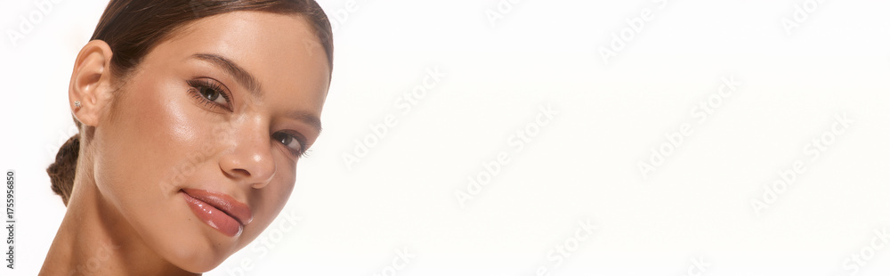 Obraz premium Captivating young woman with natural makeup glowing against a plain backdrop