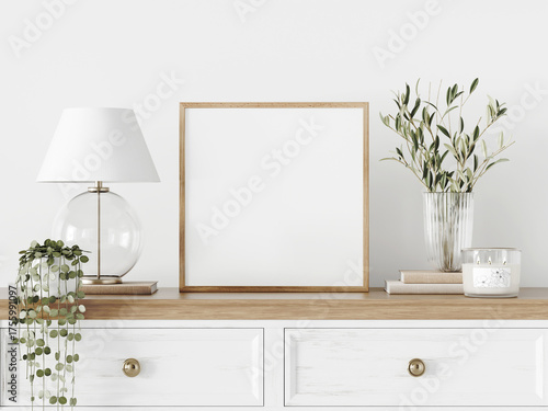 Small square frame mockup with glass lamp, branches in vase, books and candle standing on chest of drawers. Close up of classic and romantic room interior decoration. 3d rendering.